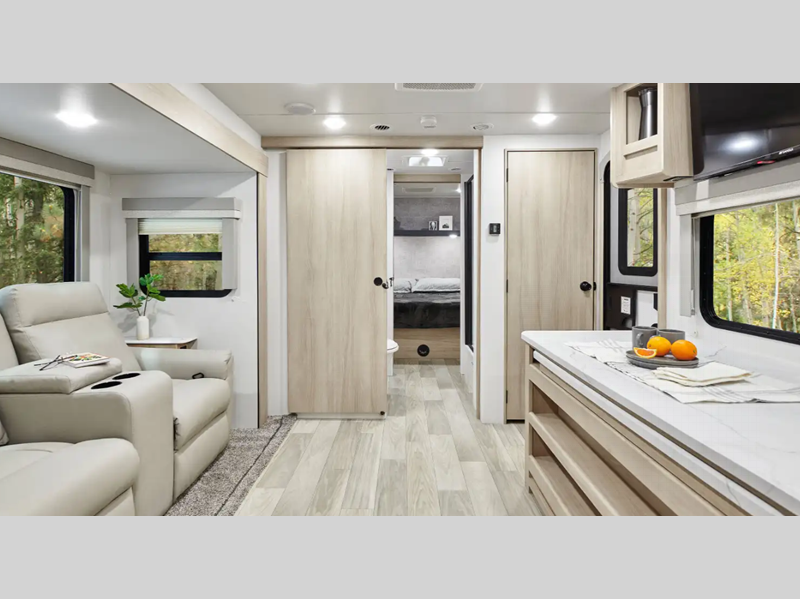 Winnebago Industries Towables Minnie Travel Trailer interior living room with recliners, a counter, and a sliding barn door to the walk-thru bathroom and master bedroom