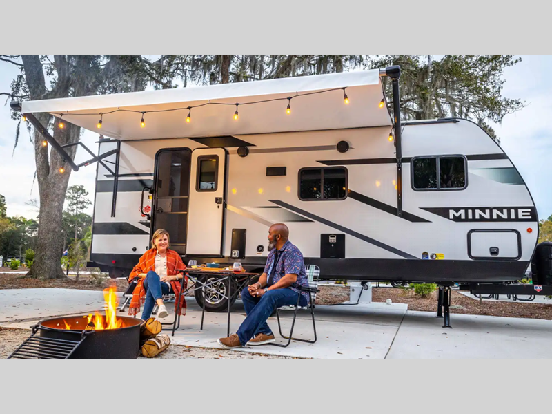 Winnebago Industries Towables Minnie Travel Trailer couple sitting outside the RV with a campfire