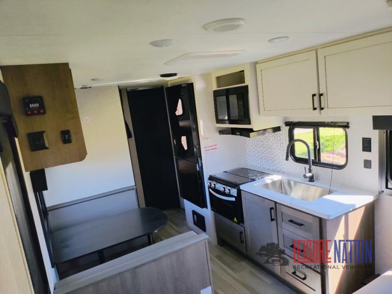 Highland Ridge RV Open Range Conventional 26BH interior view of the kitchen with a large basin sink, two-person dinette, and a rear bathroom.