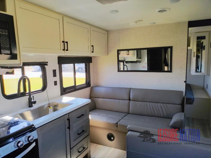 Highland Ridge RV Open Range Conventional 26BH sofa view with a mirror overhead and white storage cabinets