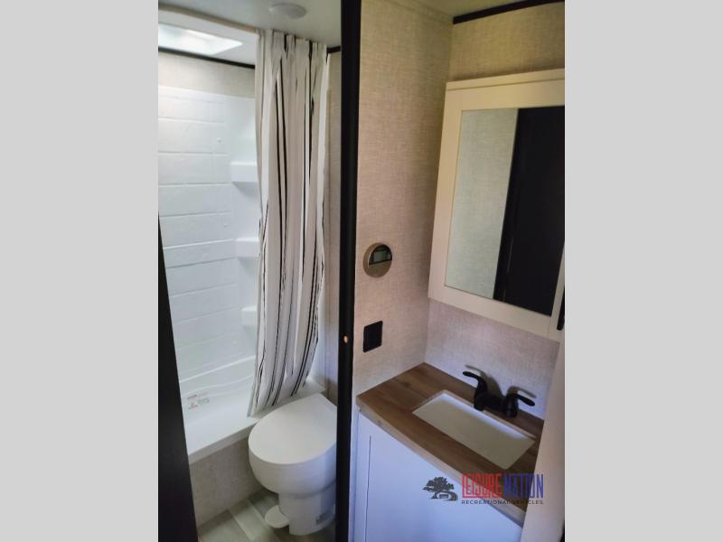 Highland Ridge RV Open Range Conventional 26BH bathroom with a separate toilet and shower area and a sink with a medicine cabinet